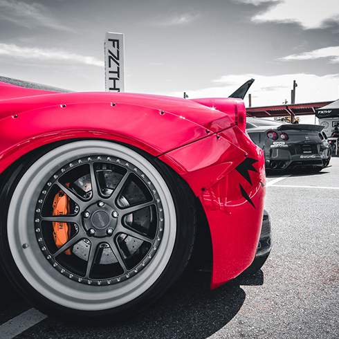 Front of a red racing car with alloy wheels and racing tyres.