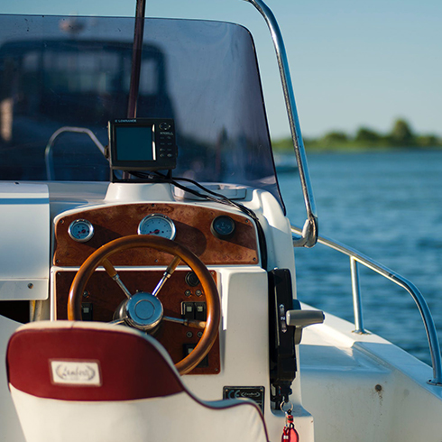 A boat, showing the steering wheel and looking out onto the water, as a concept for marine fabrication.
