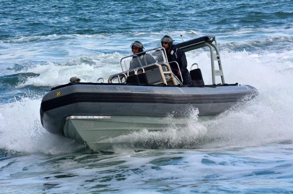 Royal Navy marine sailors travelling fast through the water in a boat